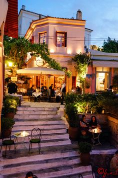 people sitting at tables in front of a building with steps leading up to the top