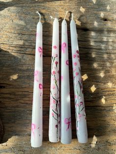 three white candles with pink flowers painted on them