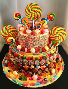 a multi layer cake covered in candy and lollipops