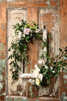 an old door decorated with flowers and greenery