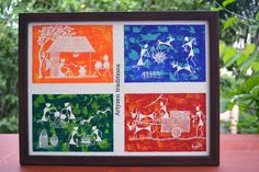 four different colored pictures in a frame on top of a wooden table next to trees