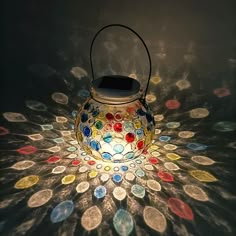 a lit up lantern sitting on top of a table covered in lots of different colored coins