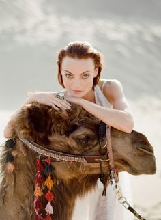 a woman is sitting on top of a camel with her arm around the back of it