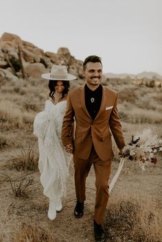 a man and woman are walking through the desert holding each other's hands as they smile