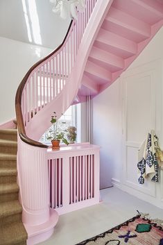 a pink staircase in a house with white walls and carpeted flooring on the ground