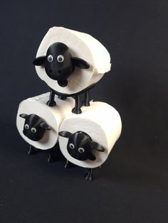 three black and white sheep standing next to each other on top of toilet paper rolls