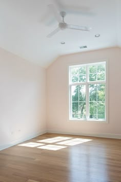 an empty room with hard wood floors and a ceiling fan in the middle of it