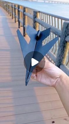 a person holding up a paper bird on a bridge