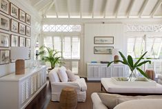 a living room filled with white furniture and lots of windows covered in shuttered shades