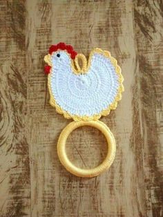 an embroidered ring with a chicken on it sitting on top of a wooden table next to a piece of wood