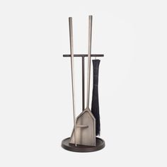 a set of three metal utensils sitting on top of a black stand with two brooms