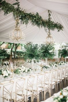 the tables are set up with white flowers and greenery for an elegant wedding reception