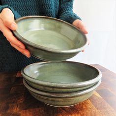 a person holding three bowls on top of a wooden table