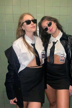 two young women dressed in black and white posing for the camera with their backs to each other