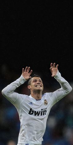 a soccer player with his hands up in the air while looking up to the sky