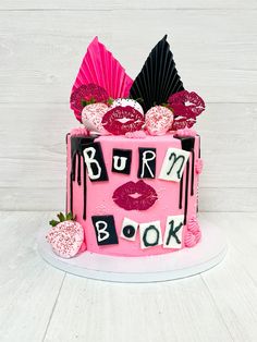 a pink cake with the words burn me book written on it and some strawberries