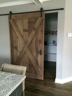 an open barn door in a kitchen with marble counter tops and wooden flooring on the side