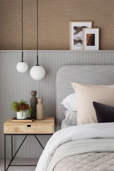 a bed sitting next to a wooden table with two vases on top of it