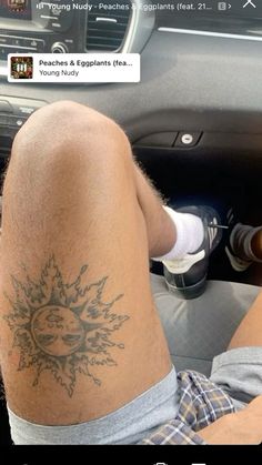 the man is sitting in his car with tattoos on his legs