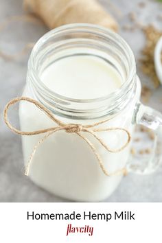 a glass jar filled with milk sitting on top of a table next to a wooden spoon