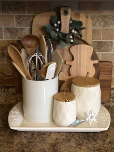 the kitchen utensils are organized in a white cup and on a tray next to a cutting board