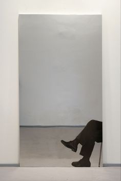 a person sitting on a chair in front of a white wall with an open doorway