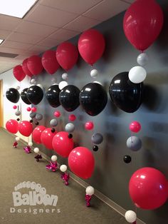 balloons and streamers are hanging from the wall in an office hallway, along with other decorations