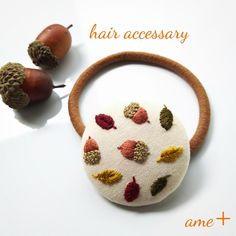 a hair accessory with leaves and acorns on it next to an acorn