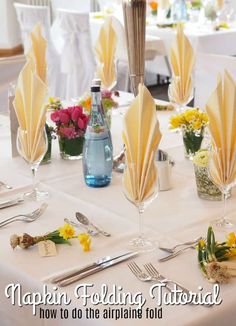 the table is set with folded napkins and flowers