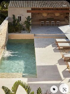 an outdoor swimming pool with lounge chairs and umbrellas