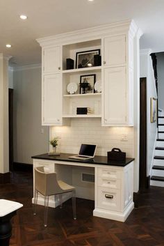 a home office with white cabinets and black counter tops, along with a staircase leading up to the second floor