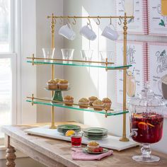 a table topped with plates and cups filled with food next to a wall mounted tea kettle