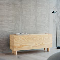 a wooden box sitting on top of a hard wood floor next to a gray wall