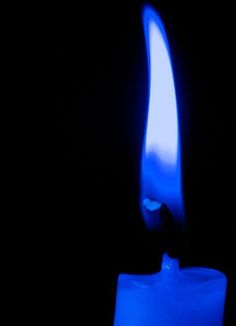 a blue candle lit up in the dark