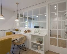 a dining room table and chairs in front of an open window with glass panes