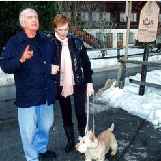 an older couple walking their dog in the snow