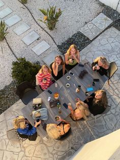 a group of women sitting around a table eating food and drinking coffee while looking up at the camera