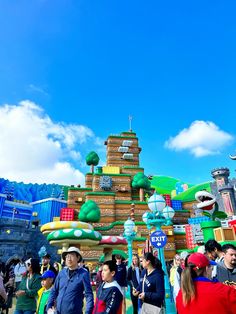 many people are standing around in front of an amusement park ride at the theme park