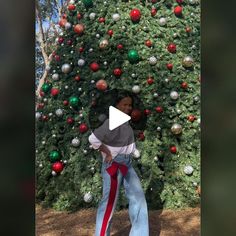 a woman standing in front of a christmas tree with red, green and silver ornaments