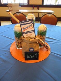 a baseball themed centerpiece on top of a blue table cloth with an orange plate