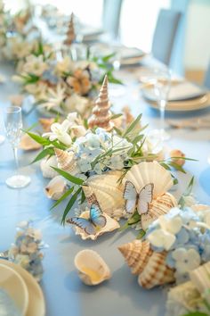 the table is set with shells and flowers