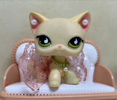 a small toy cat sitting on top of a white table next to a pink chair