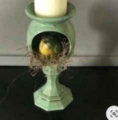 a green candle holder with a bird nest in it