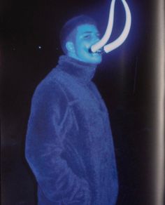 a man is standing in the dark with a neon light on his face and mouth