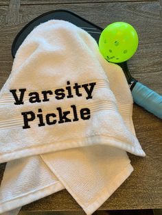 a towel with the words varsity pickle on it next to a pair of tennis racquets