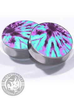 two round tins with purple and blue tie - dye designs on the top one is empty