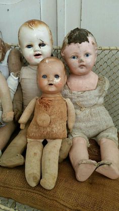 three old dolls sitting next to each other