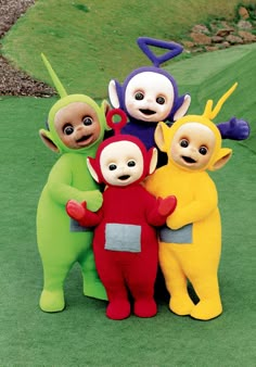 five stuffed animals are posed together on the green grass in front of a golf course