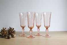 four wine glasses sitting on top of a wooden table next to pine cones and a pine cone