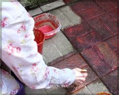 a person is painting the sidewalk with red paint and water in buckets on it